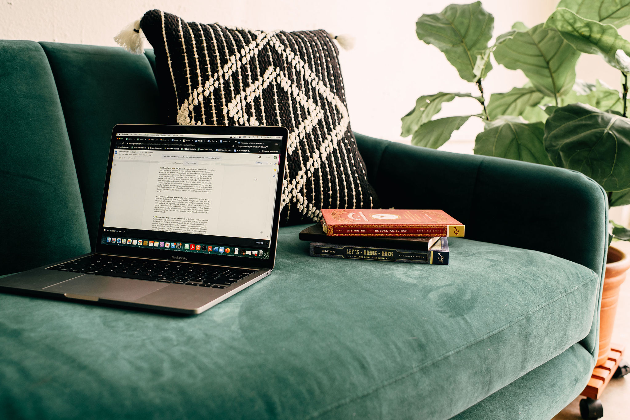 A laptop and books sit on a couch. WhitneyWroteThis.com discusses the importance of hiring a copywriter to create ethical website copy for your business.