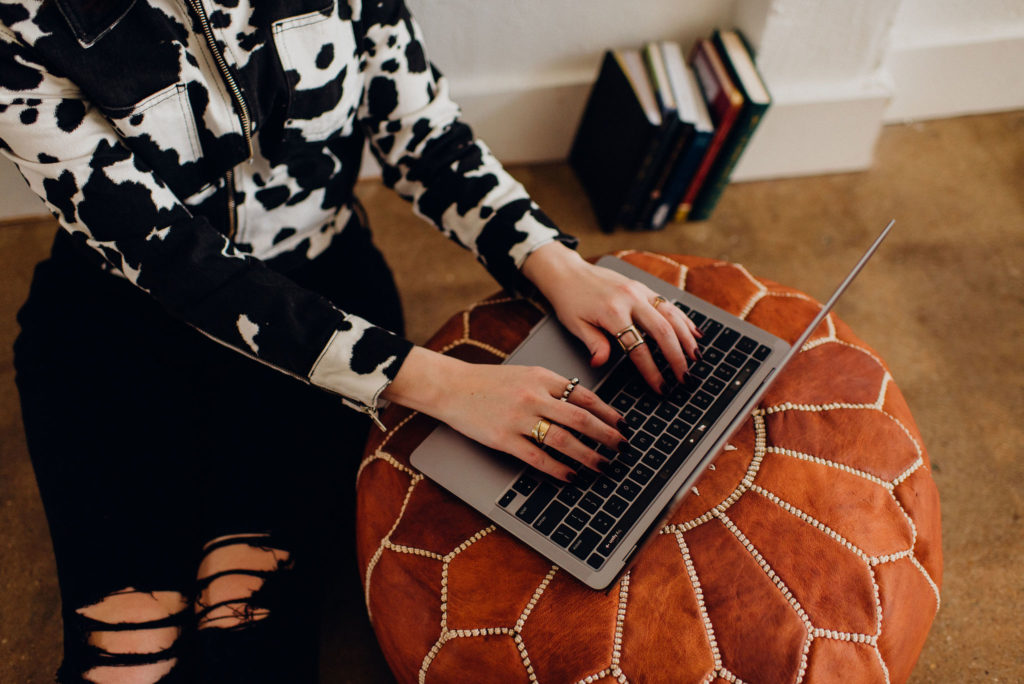 Copywriter Whitney Falloon types on her laptop. In her blog, she explains when it's time to outsource copywriting for your biz.